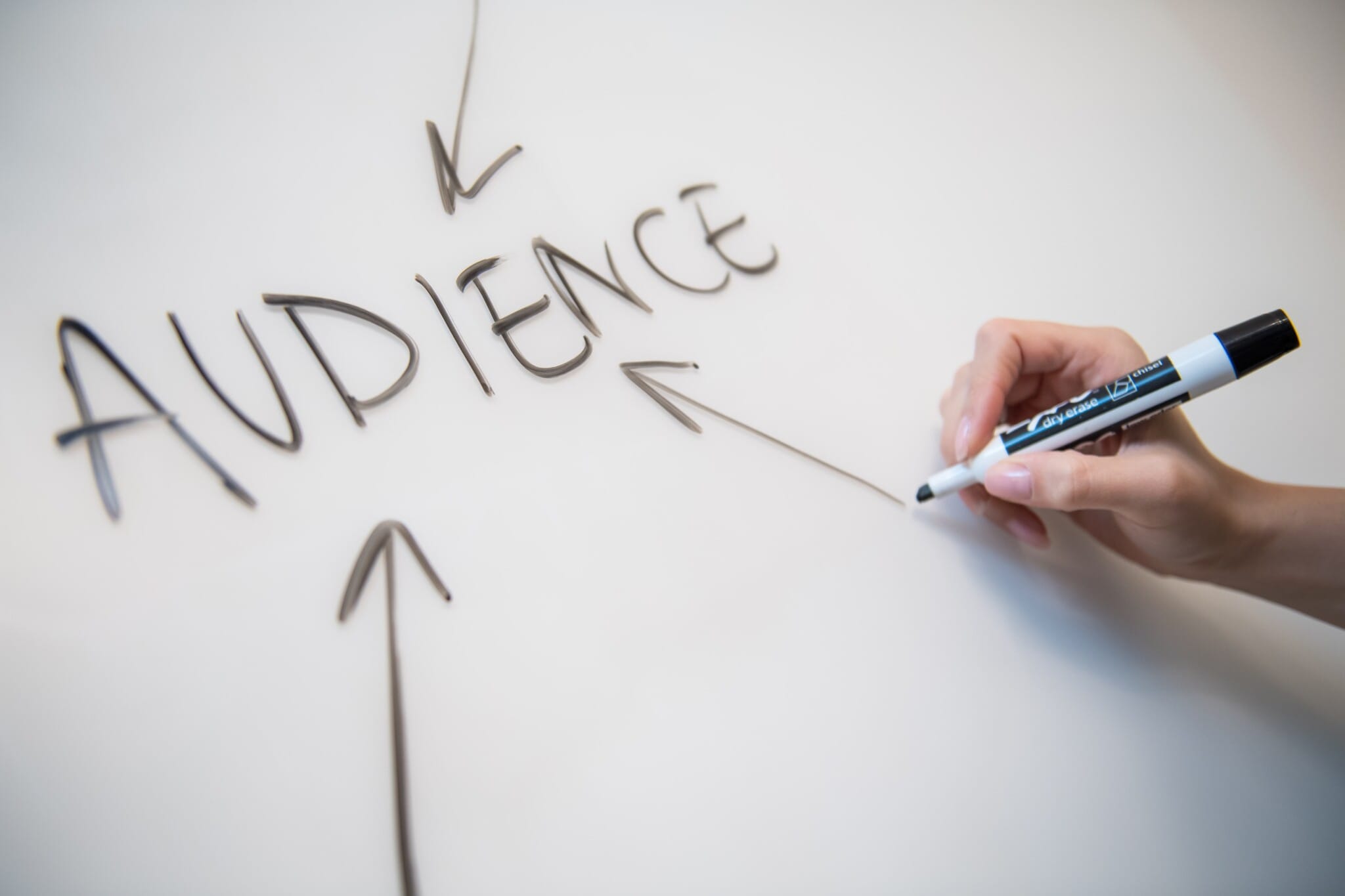 womans hand writing the word audience on a whiteboard with arrows stockpack unsplash